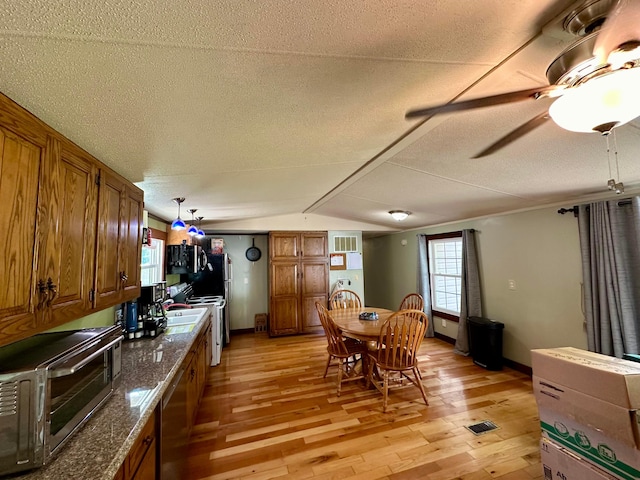 dining space with light hardwood / wood-style floors, a textured ceiling, and vaulted ceiling