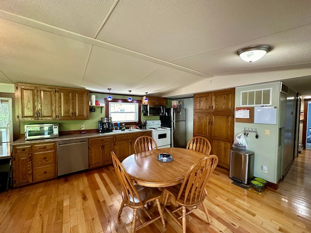 kitchen featuring a textured ceiling, stainless steel appliances, vaulted ceiling, and light hardwood / wood-style floors