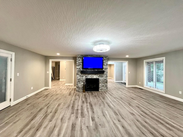 unfurnished living room featuring a fireplace, light hardwood / wood-style floors, and a textured ceiling