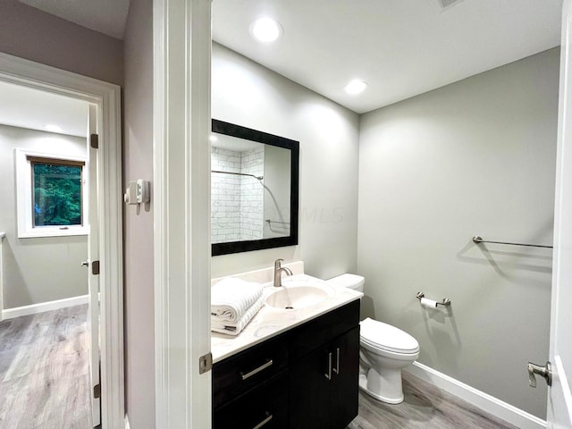 bathroom featuring vanity, toilet, wood-type flooring, and tiled shower