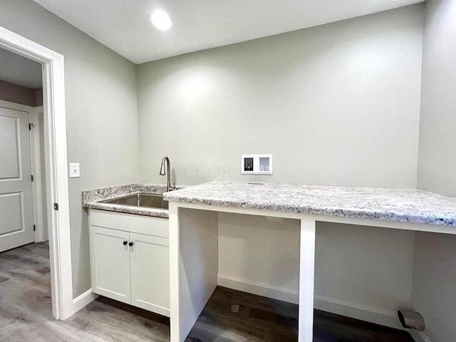 kitchen featuring light stone counters, wood-type flooring, and sink