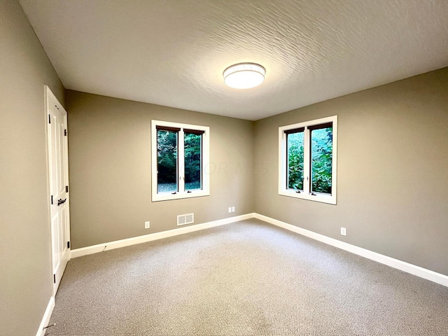 carpeted empty room with a textured ceiling