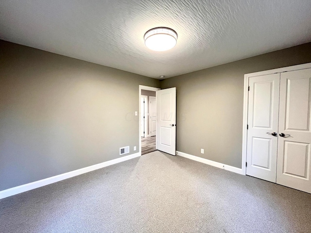 unfurnished bedroom featuring carpet, a textured ceiling, and a closet