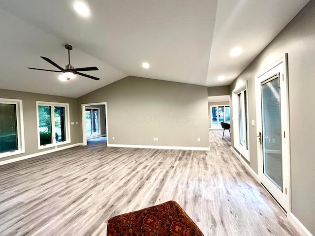 unfurnished living room featuring ceiling fan, light hardwood / wood-style floors, lofted ceiling, and a healthy amount of sunlight