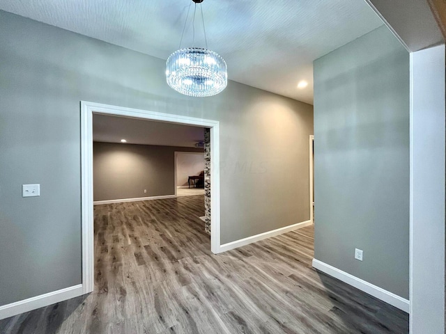 unfurnished dining area with hardwood / wood-style floors and a notable chandelier