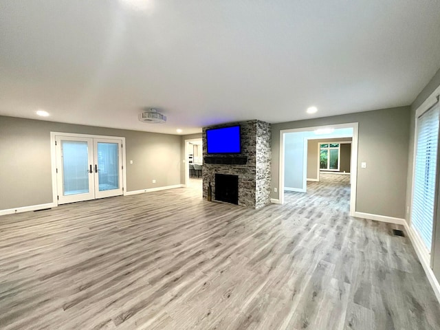 unfurnished living room with french doors, a fireplace, and light hardwood / wood-style flooring