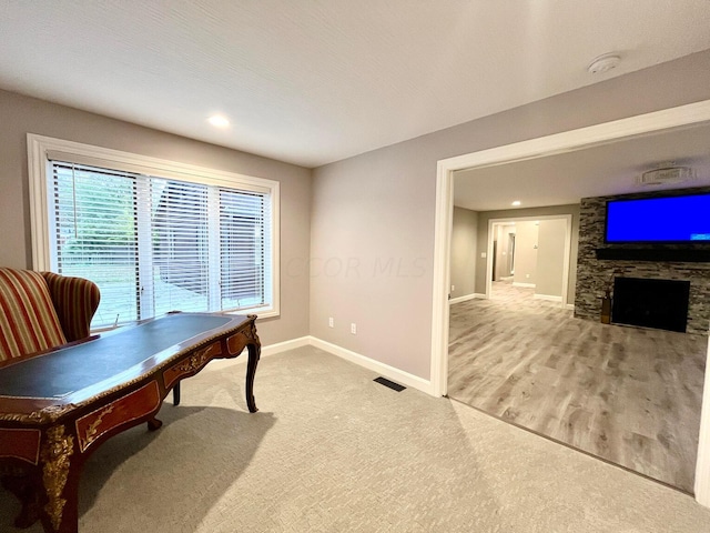 office area with a stone fireplace, light hardwood / wood-style flooring, and a textured ceiling