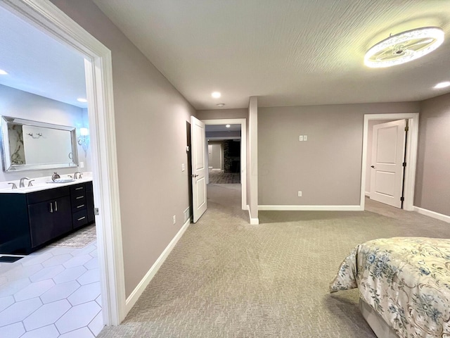 bedroom with ensuite bathroom, sink, and light carpet