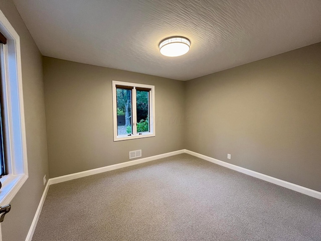 carpeted spare room with a textured ceiling