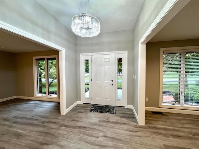 foyer entrance with wood-type flooring and an inviting chandelier