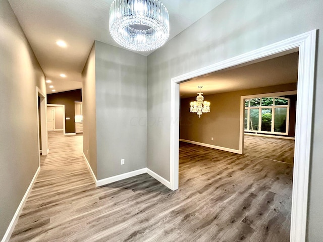 hallway featuring hardwood / wood-style floors, a chandelier, and lofted ceiling