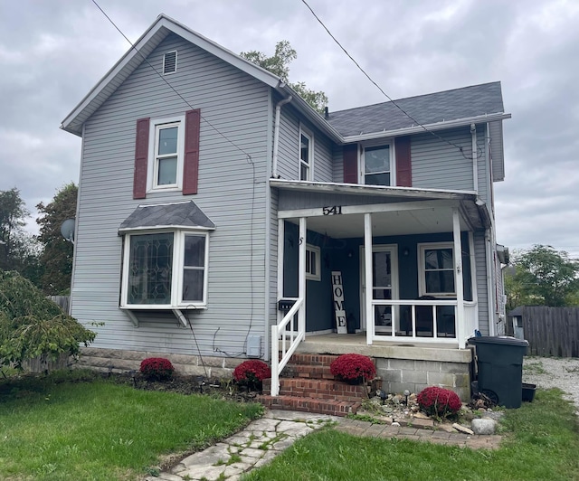 front facade featuring covered porch and a front yard