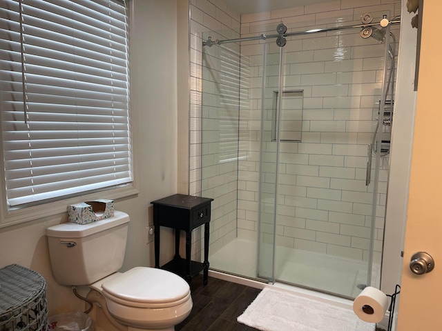 bathroom with hardwood / wood-style floors, a shower with door, and toilet