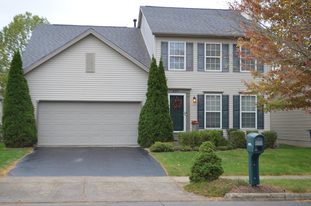 view of front of property featuring driveway, roof with shingles, a garage, and a front yard