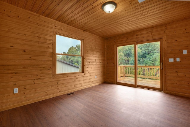 unfurnished room featuring light hardwood / wood-style floors, a wealth of natural light, and wooden walls