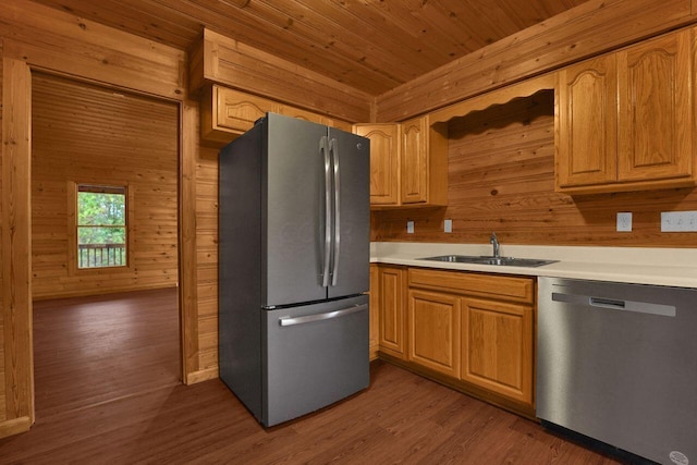 kitchen with hardwood / wood-style floors, stainless steel appliances, wooden walls, and sink