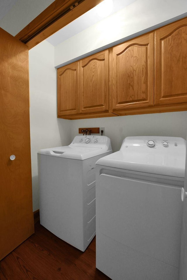 clothes washing area featuring cabinets, washer and dryer, and dark wood-type flooring