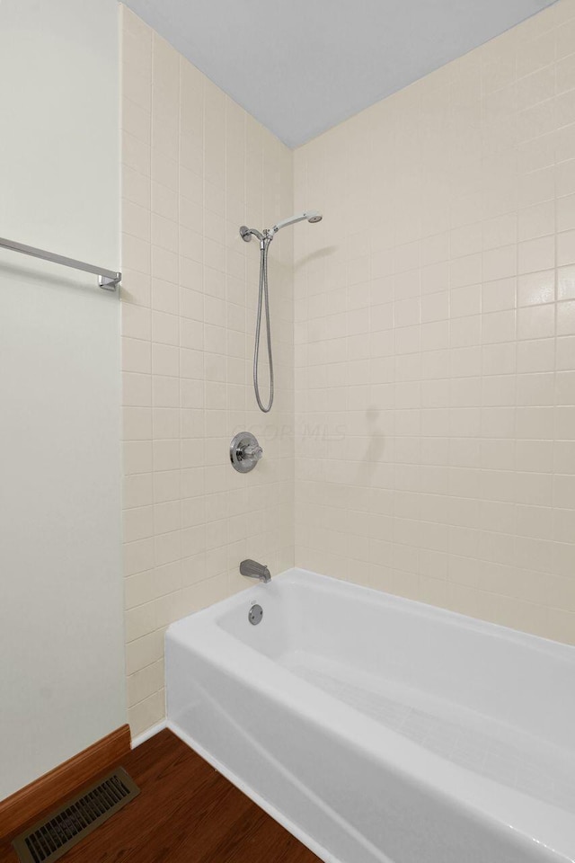 bathroom featuring wood-type flooring and tiled shower / bath