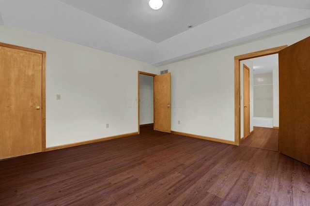 unfurnished room featuring dark hardwood / wood-style floors and vaulted ceiling