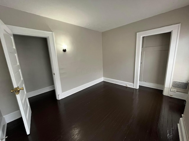 unfurnished bedroom featuring a closet and dark wood-type flooring