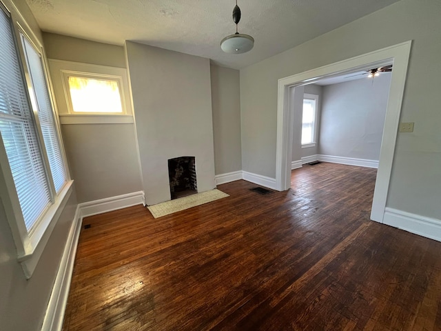 unfurnished living room featuring a textured ceiling, a wealth of natural light, and dark hardwood / wood-style floors