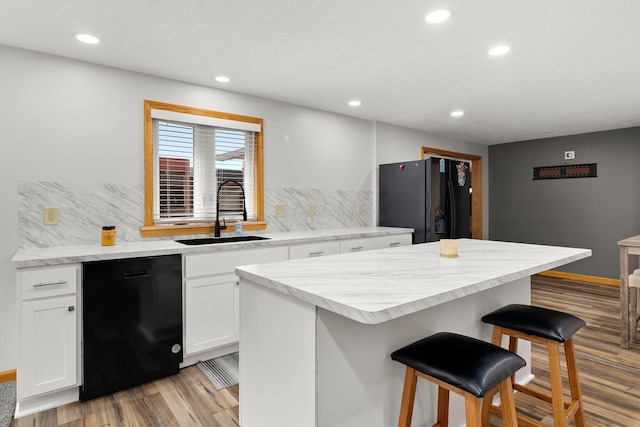 kitchen featuring white cabinetry, sink, a center island, a breakfast bar area, and black appliances