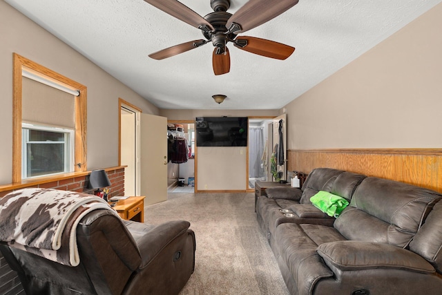 living room featuring a textured ceiling, light colored carpet, ceiling fan, and wood walls