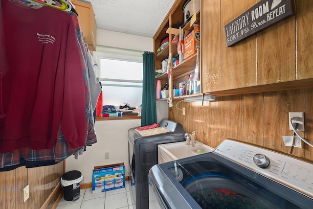 washroom with wood walls, sink, independent washer and dryer, a textured ceiling, and light tile patterned floors