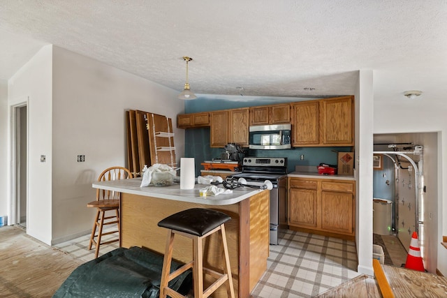 kitchen with vaulted ceiling, a textured ceiling, decorative light fixtures, light hardwood / wood-style floors, and stainless steel appliances