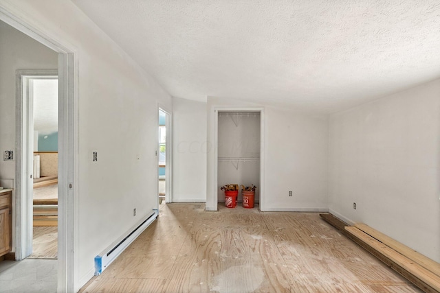 empty room featuring a textured ceiling, light hardwood / wood-style floors, and baseboard heating