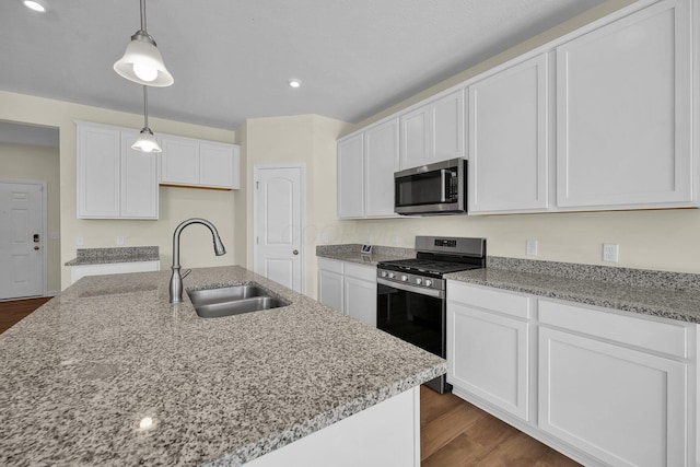 kitchen featuring white cabinets, sink, hanging light fixtures, dark hardwood / wood-style flooring, and stainless steel appliances