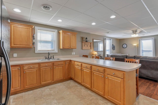 kitchen featuring kitchen peninsula, ceiling fan, sink, light hardwood / wood-style flooring, and fridge