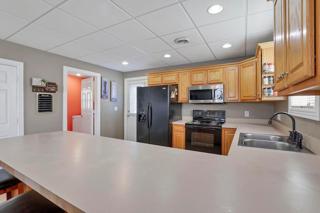 kitchen featuring sink, kitchen peninsula, a breakfast bar area, a paneled ceiling, and black appliances