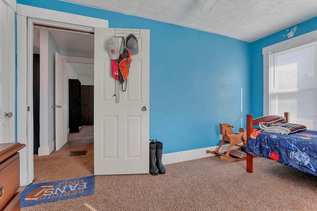 bedroom with ceiling fan, carpet floors, and a textured ceiling