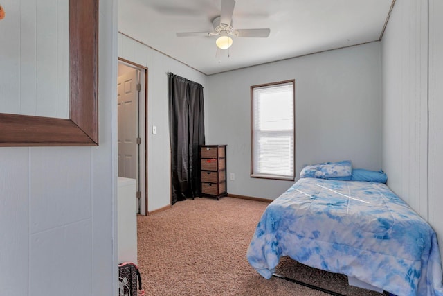 carpeted bedroom featuring ceiling fan and wood walls