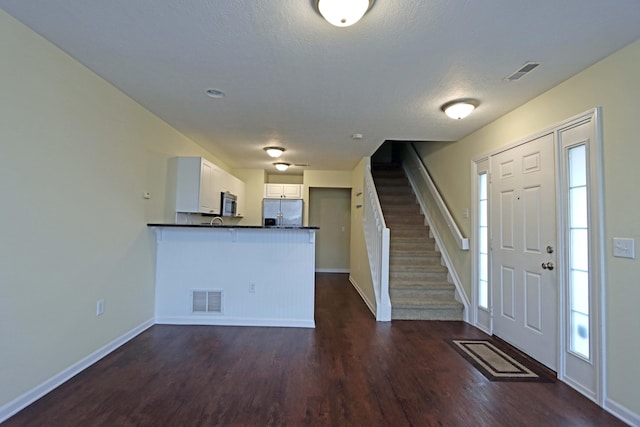 entryway featuring dark wood-style flooring, visible vents, baseboards, and stairs