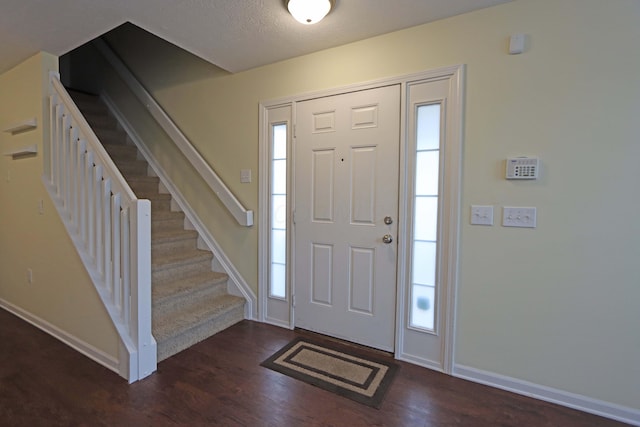 foyer entrance featuring dark wood-style floors, stairway, baseboards, and a textured ceiling