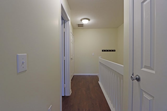 corridor featuring baseboards, visible vents, and dark wood finished floors