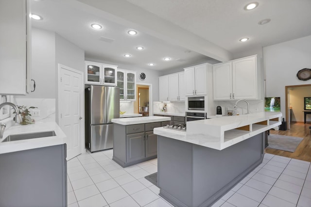 kitchen with sink, gray cabinets, appliances with stainless steel finishes, a kitchen island, and white cabinetry