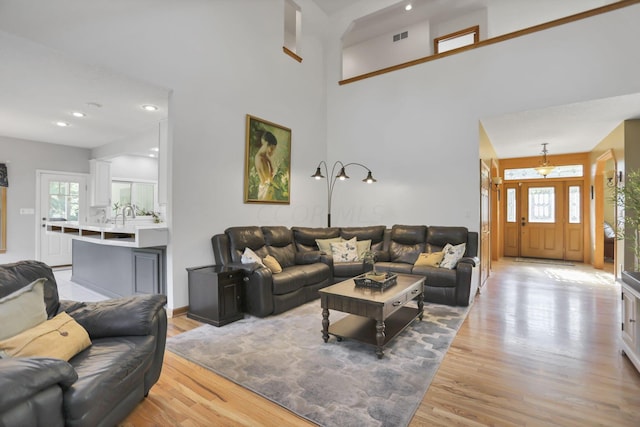 living room with light hardwood / wood-style floors and a towering ceiling