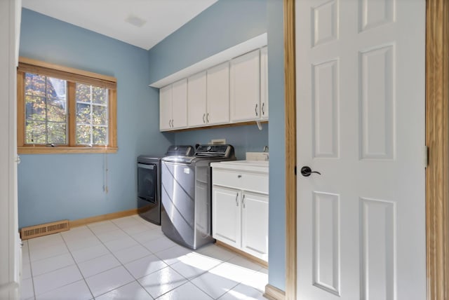 clothes washing area with cabinets, independent washer and dryer, and light tile patterned floors