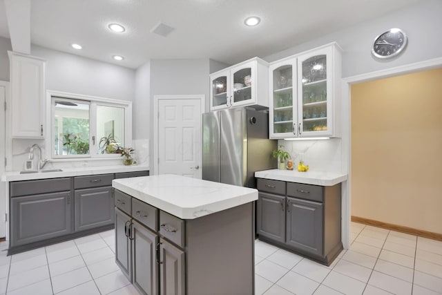 kitchen featuring gray cabinetry, white cabinetry, stainless steel refrigerator, and sink