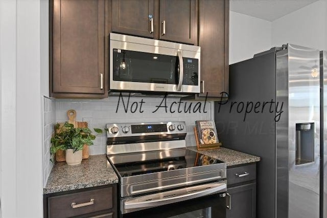 kitchen featuring backsplash, dark stone countertops, dark brown cabinets, and appliances with stainless steel finishes