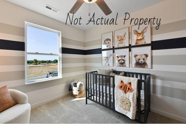 bedroom with carpet, ceiling fan, and a crib