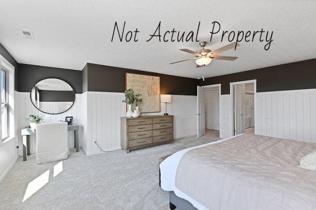 bedroom with ceiling fan, light colored carpet, and a textured ceiling