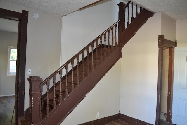 staircase featuring a textured ceiling and hardwood / wood-style flooring