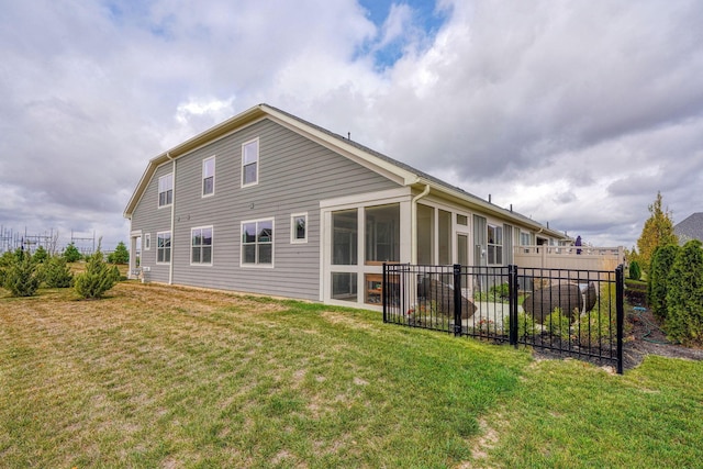 rear view of house featuring a lawn and a sunroom