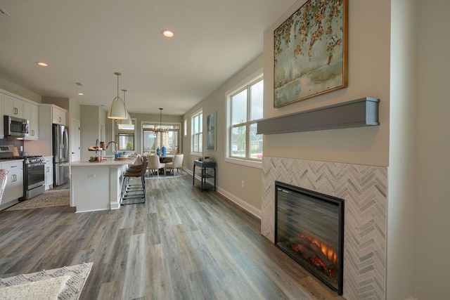 kitchen featuring a center island with sink, hanging light fixtures, a kitchen bar, white cabinetry, and stainless steel appliances