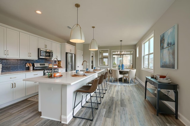 kitchen with white cabinets, an island with sink, and stainless steel appliances