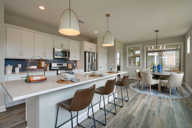 kitchen featuring pendant lighting, stainless steel appliances, white cabinetry, and a spacious island